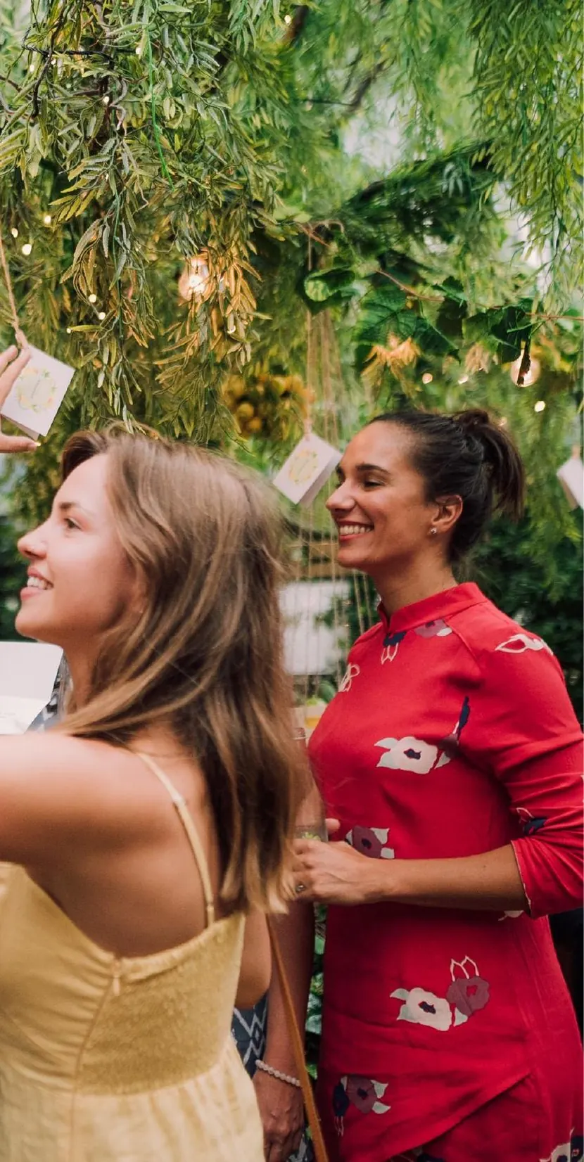 Two guests laughing at a party under hanging garlands.